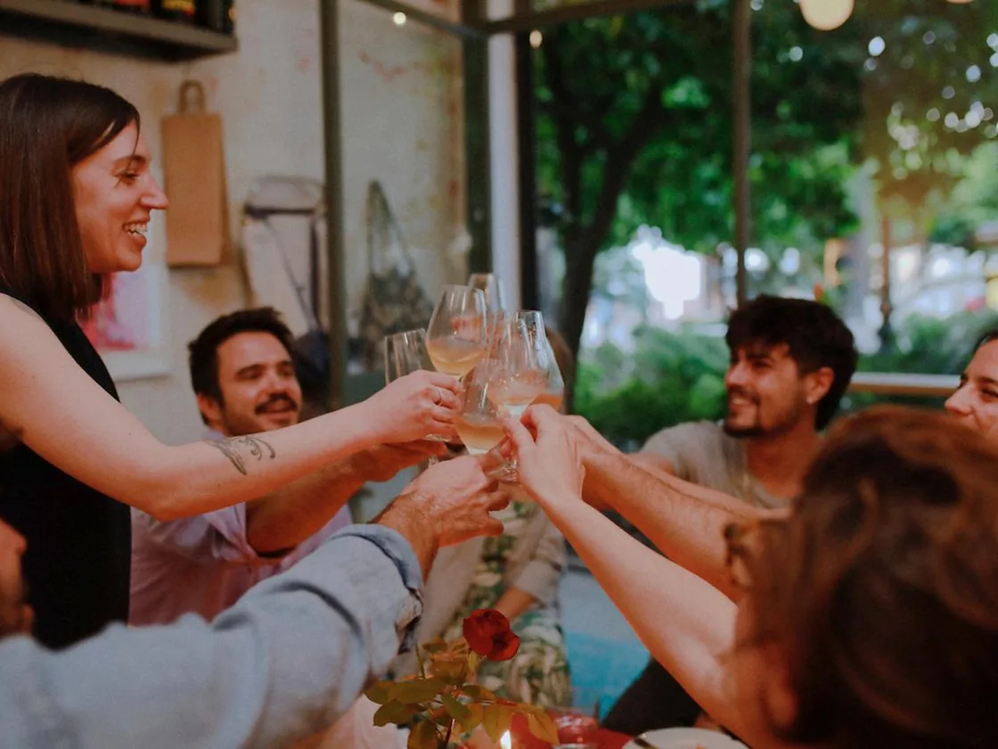 Un grupo brindando con copas de vino en la mesa de Jugo, al atardecer
