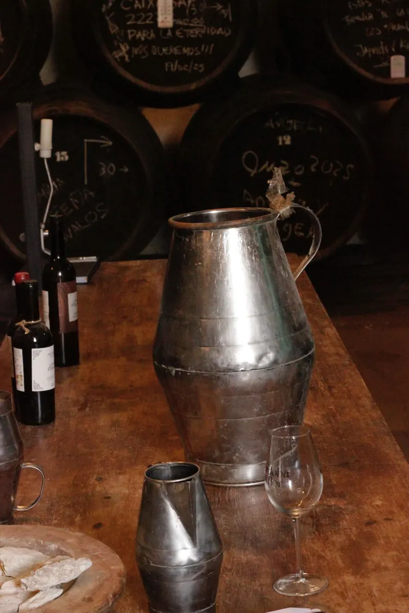 Una jarra de metal sobre la mesa de la bodega, delante de las barricas